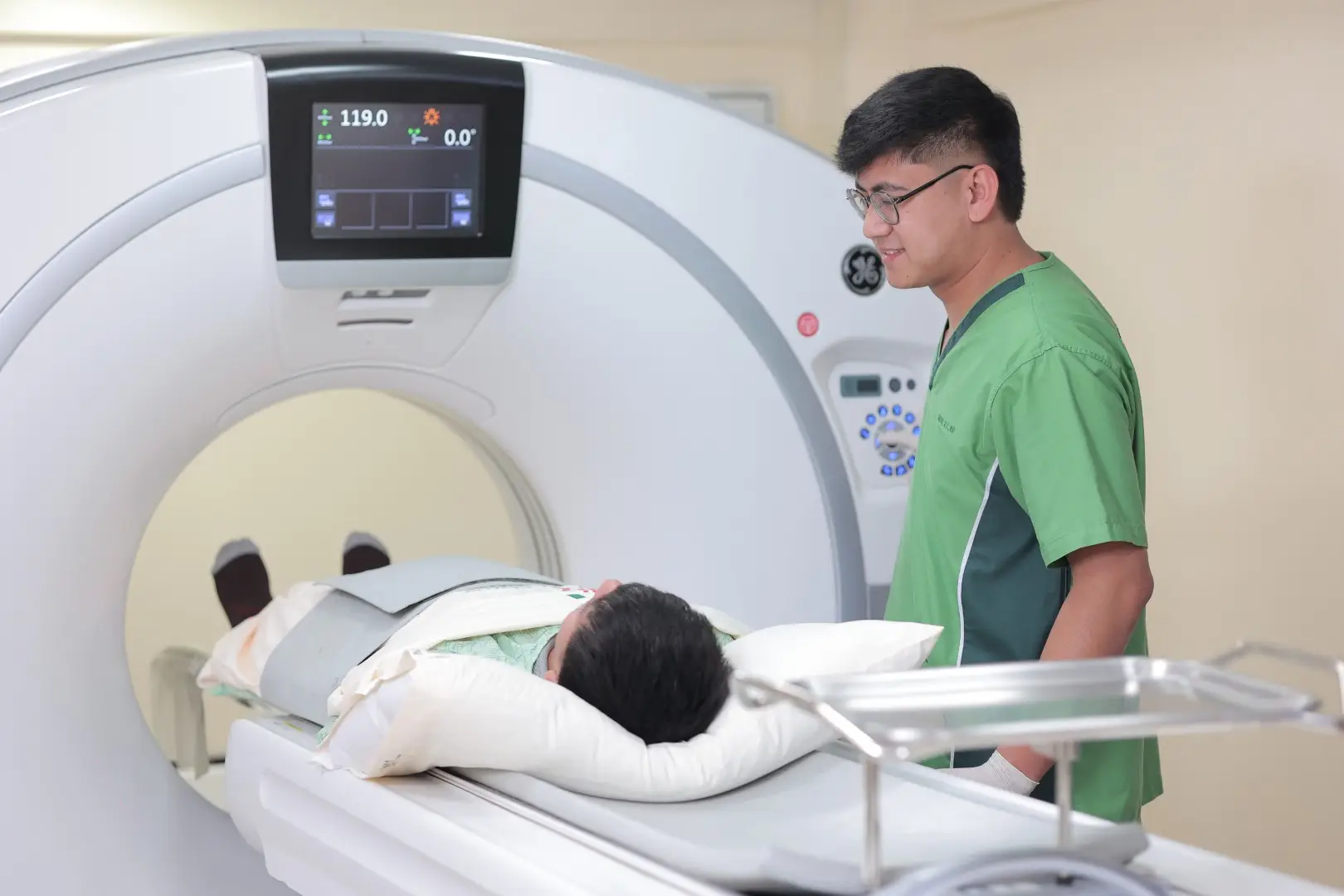 Patient undergoing CT scan with clinician monitoring.